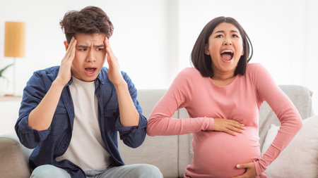 Pregnant Wife Shouting Touching Belly Sitting With Shocked Husband Indoor