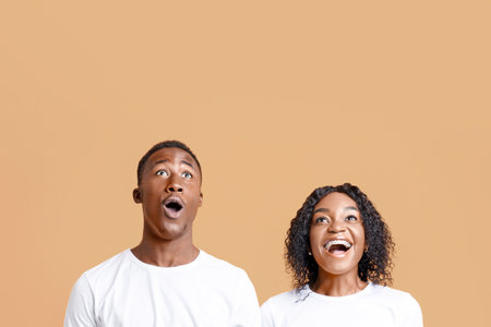 Amazed black couple looking up at copy space