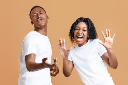 Emotional black man and woman dancing and singing on yellow