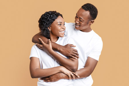 Happy black man and woman embracing, looking at each otherの写真素材
