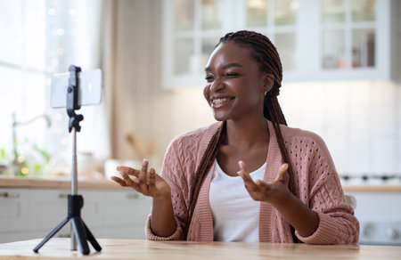 Black Female Blogger Recording Video In Kitchen With Smartphone On Tripodの写真素材