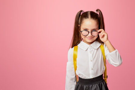 First school day. Cheerful girl in uniform takes off glasses and looks at camera