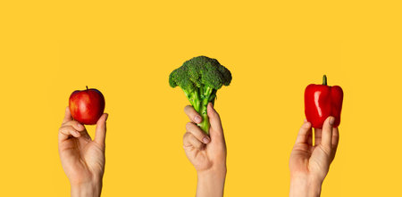 Collage with male hands holding broccoli, bell pepper and apple on orange background, close upの写真素材