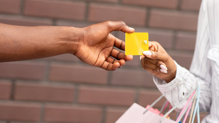 Girl shopper with colored bags gives credit card to seller