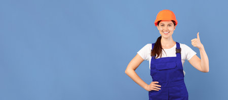 Portrait Of Young Handywoman Lady In Hardhat And Coveralls Showing Thumb Upの写真素材
