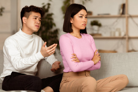 Asian Boyfriend Talking To Offended Girlfriend After Quarrel At Homeの写真素材