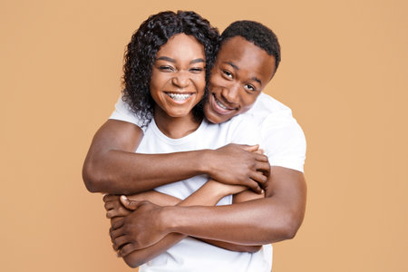 Loving black couple cuddling on yellow background