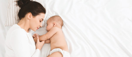 Young mom and her cute baby sleeping in bedの写真素材