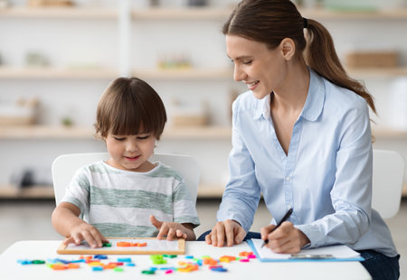 Professional woman language teacher exercising with preschooler, little boy making word with letters, free spaceの写真素材