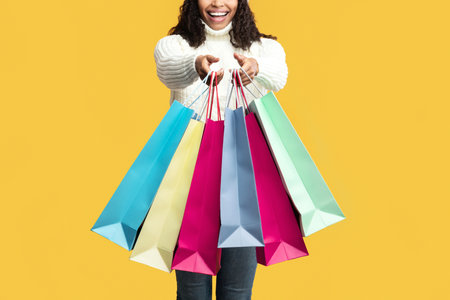 Overjoyed black woman showing shopping bags at studio