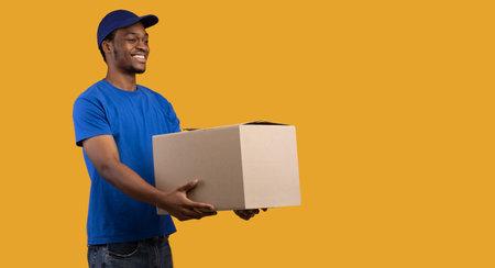 Black delivery guy holding cardboard box giving it to sideの写真素材