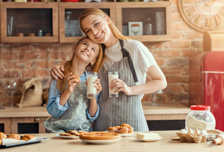 Happy mother and daughter bonding while drinking milk after cookingの写真素材