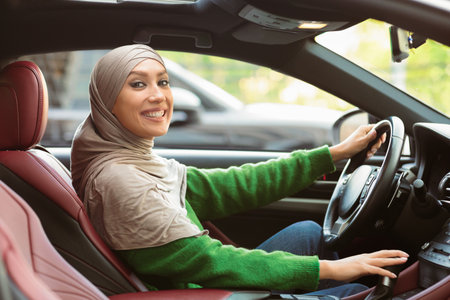 Smiling muslim woman driving her new carの写真素材