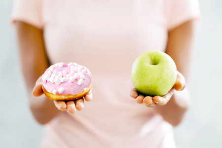 Choice of healthy or junk food. Closeup view of black woman choosing between donut and apple on...