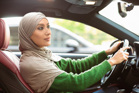 Cheerful muslim woman driving her new carの写真素材