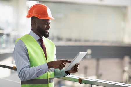Smiling african american civil engineer with digital tablet, side view