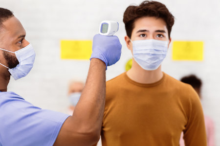 Nurse Doing Temperature Screening For Asian Man Patient In Hospital