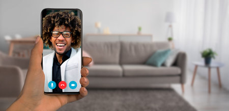 Person engaging in video call from home using smartphone on a comfortable couchの写真素材