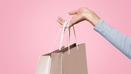 Hand of african american woman holding blue and yellow bagsの写真素材