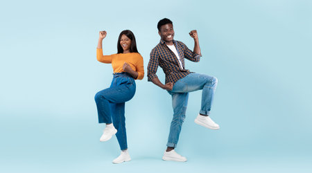 Portrait of excited young black couple shaking clenched fists
