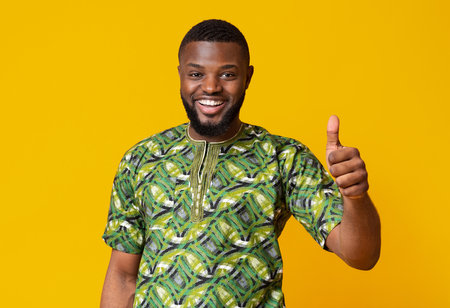 Black guy showing thumbs up over yellow studio backgroundの写真素材