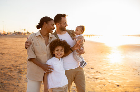 Beachside bonding. Happy multiracial family walking and enjoying time together on beach during holidaysの写真素材