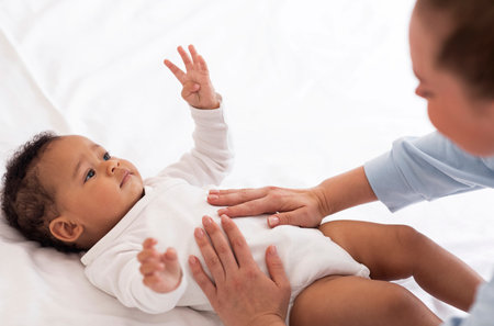 Masseur Lady Making Massage To Cute Little Black Baby Lying On Bedの写真素材
