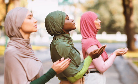 Three Islamic Ladies Praying Standing Together Outside Wearing Traditional Hijab