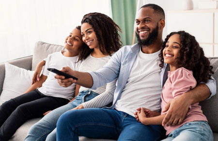 Happy young black family watching television sitting on sofa
