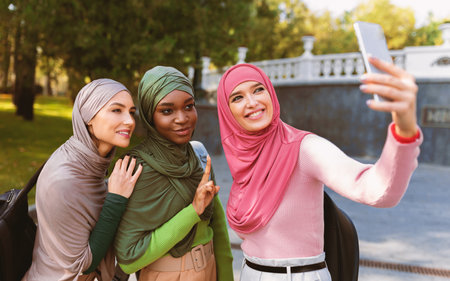 Three Modern Islamic Ladies Making Selfie On Phone In Parkの写真素材