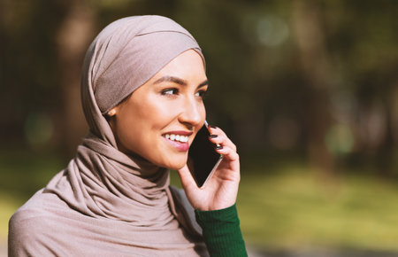 Happy Muslim Woman Talking On Phone Calling Friend Standing Outdoorsの写真素材