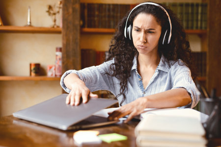 Tired woman sitting at desk, closing or opening laptop