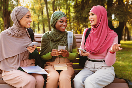Muslim Women Using Phones Talking And Having Fun In Parkの写真素材