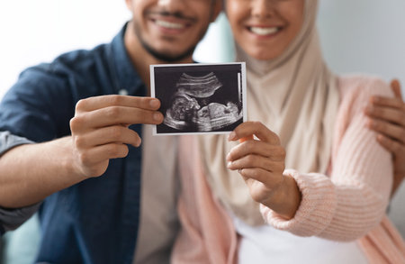 Closeup shot of happy pregnant muslim couple demonstrating baby sonography photo