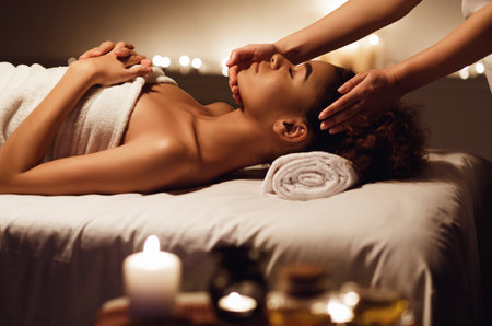 African girl having face massage, relaxing in spa salonの写真素材