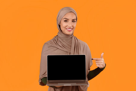 Muslim Lady Pointing At Laptop Empty Screen, Yellow Background, Mockup