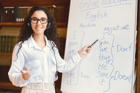 Smiling female teacher standing near whiteboard, explaining rulesの写真素材