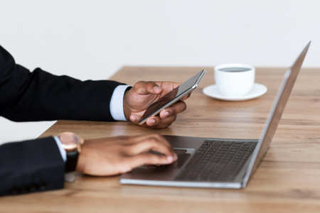 Cropped of black man businessman working in office, using gadgetsの写真素材