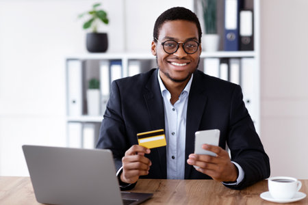 Happy black man holding credit card and smartphoneの写真素材
