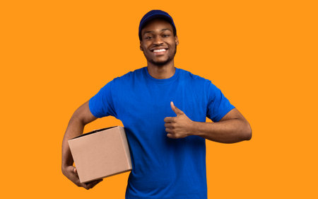 Black delivery man holding cardboard box showing thumb upの写真素材