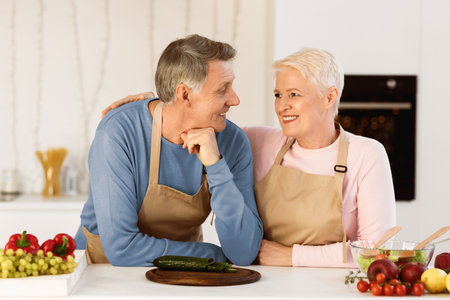 Elderly Spouses Embracing Preparing Dinner Standing In Modern Kitchenの写真素材