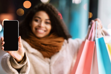 Happy black woman showing smartphone with blank empty screen mockupの写真素材