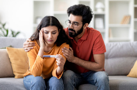 Infertility Problems. Portrait Of Upset Indian Couple Looking At Negative Pregnancy Testの写真素材