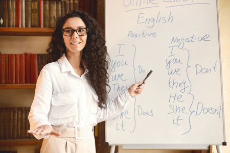 Smiling female teacher pointing at whiteboard, explaining rulesの写真素材