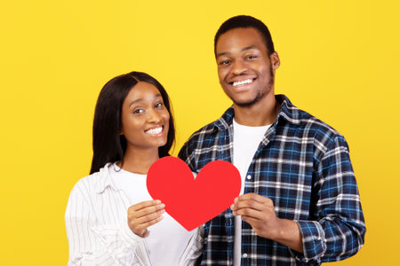 Smiling millennial african american guy and lady hold red heart at self-isolationの写真素材