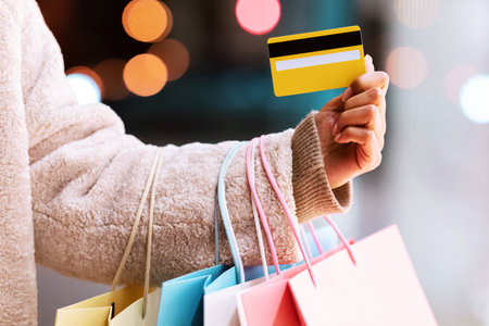 Unrecognizable black lady holding credit card and shopping bagsの写真素材