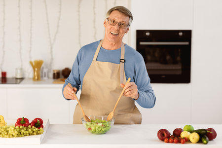 Senior Man Cooking Standing Smiling To Camera In Modern Kitchenの写真素材