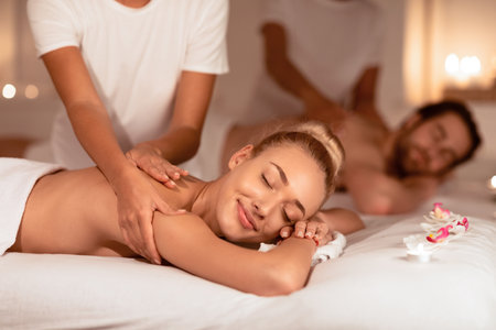 Happy Couple Relaxing Lying In Luxury Spa Receiving Back Massageの写真素材