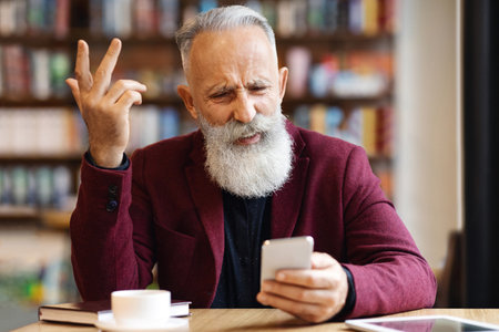 Senior man using mobile phone at cafe