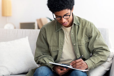 Distance learning concept. Industrious black male student studying from home during coronavirus...
